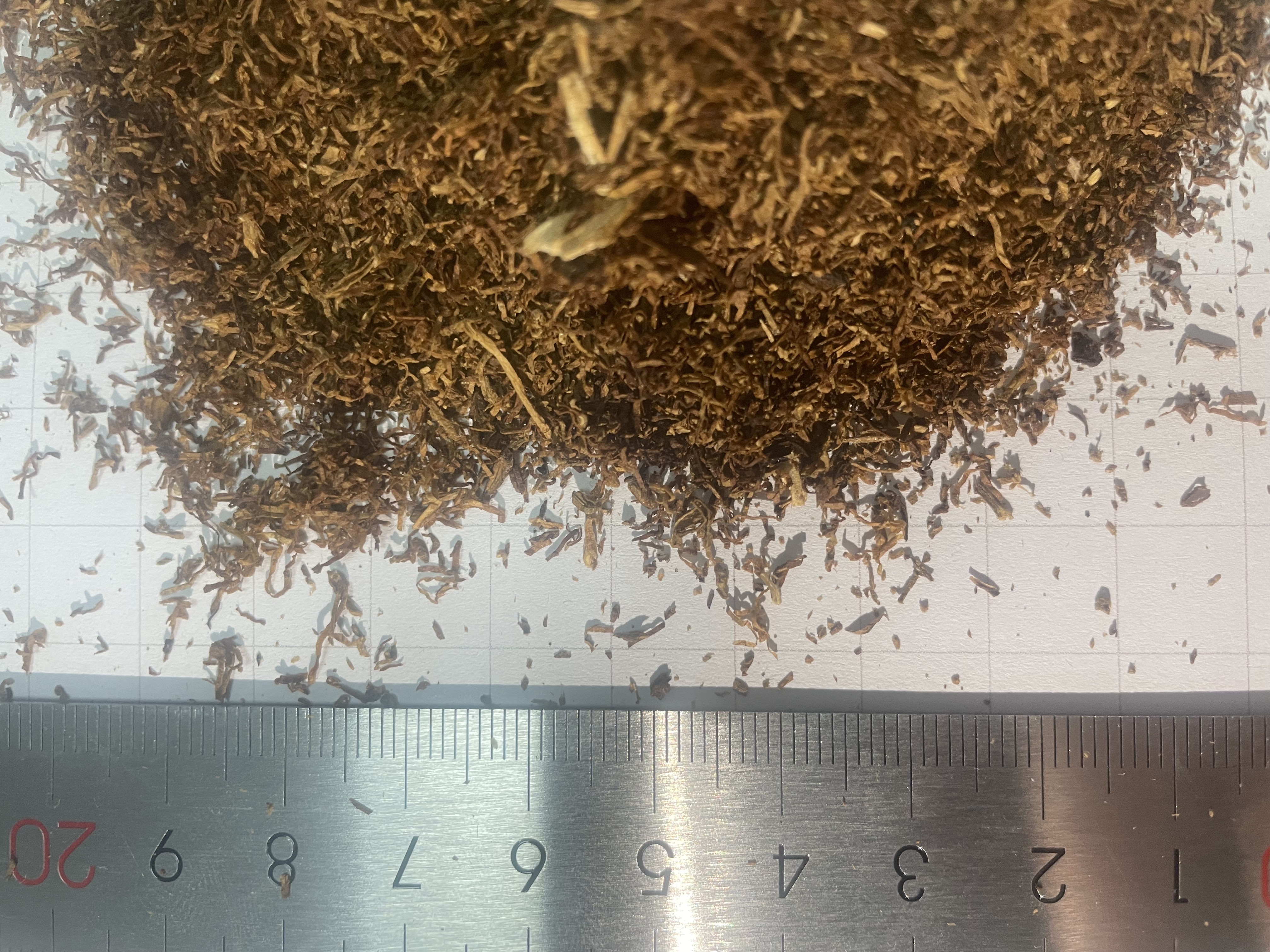 Close view of tobacco strands beside a ruler
